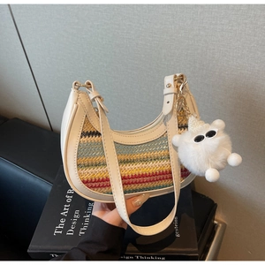 Detail of colorful striped woven straw bag with cream leather trim and plush charm