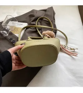 Détail du mini sac cabas vert avocat avec breloque à pompon et texture en cuir PU grainé