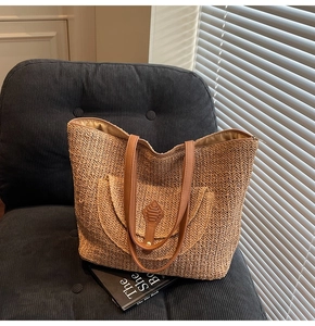 Detail of hand-woven straw tote bag with brown leather straps and front pocket