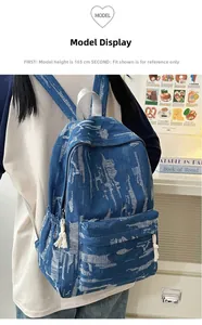 Detail of distressed blue denim backpack with side pocket and woven rope zipper pull