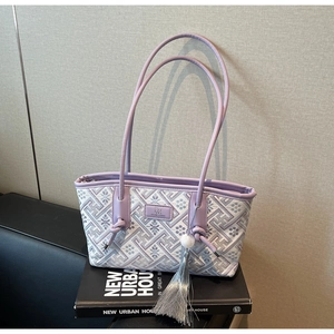 Makrodetail der lila Jacquard-Tragetasche mit geometrischen Blumenmustern und Quastenanhänger
