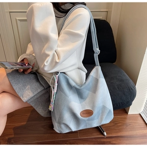 Détail du sac hobo bleu clair avec motifs géométriques, logo en cuir et bandoulière
