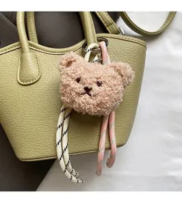Détail d'un charme d'ours en peluche avec cordons tissés sur un sac seau en cuir vert