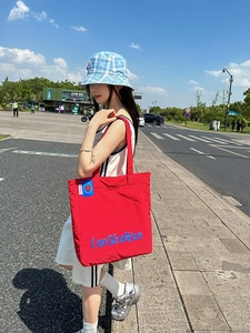 Vue de rue d'un grand sac cabas en nylon rouge avec des lettres graphiques bleues