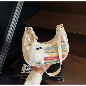 Detail of white half-moon straw bag with colorful wavy weave and cute plush charm