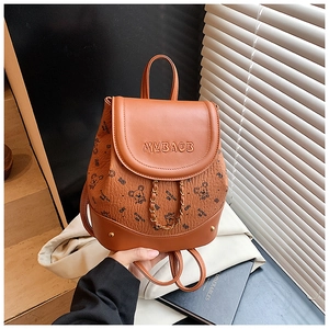 Detail of brown leather backpack featuring bear pattern print and gold chain strap decoration