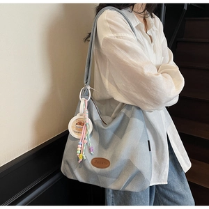Détail du sac fourre-tout en denim jacquard bleu clair avec logo et breloque capybara