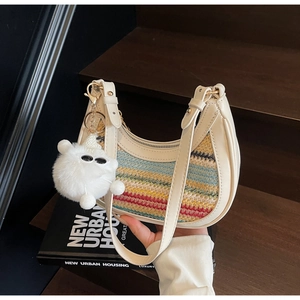 Detail of colorful woven straw bag with cream leather trim and plush cat charm