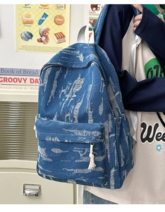 Detail of blue denim backpack showing vintage distressed texture and side tassel charm