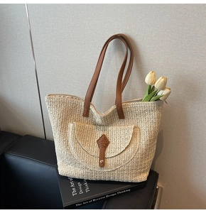 Detail of woven straw tote bag with brown leather strap and front pocket detail