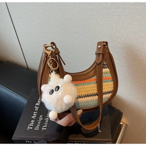 Detail of a brown leather saddle bag with colorful knit wave patterns and a plush charm