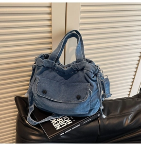 Detail der blauen Denim-Tragetasche mit Kordelzug und großen Klappentaschen vorne