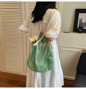 Detail van groene mesh shopper met roze bies, geweven banden en tulp binnen