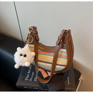 Detail of colorful woven shoulder bag with leather trim and plush monster charm