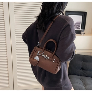 Dettaglio borsa in pelle marrone con chiusura girevole e ciondolo a forma di cuore