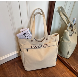 Detail of canvas tote bag showing front zipper pocket and TAOCAITU branding