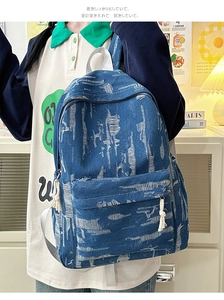 Close-up of vintage distressed blue denim backpack with ripped frayed details and front pocket