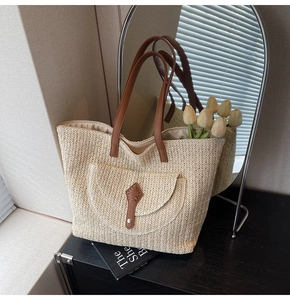 Detail of woven straw tote bag with brown leather straps and front pocket