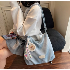 Détail d'un sac cabas en jean bleu clair avec breloque capybara et logo Banatu
