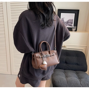 Dettaglio della borsa in pelle martellata marrone con chiusura in metallo e charm a cuore