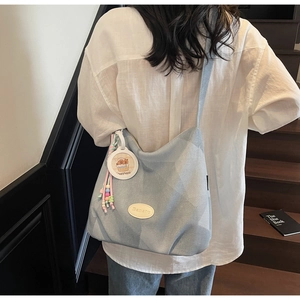 Détail du grand sac cabas en jean bleu clair avec breloque capybara et logo en cuir