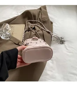 Détail d'un sac boîte rose matelassé avec bandoulière chaîne argentée et décor d'étoiles