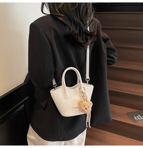 Détail du mini sac blanc en cuir litchi avec breloque ours et logo doré élégant