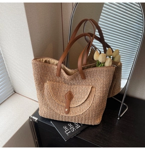 Detail of woven straw tote bag featuring brown leather handle and front flap pocket