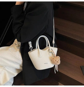 Détail d'un sac seau en cuir litchi blanc avec un joli petit pendentif d'ours