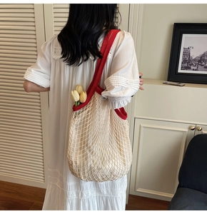 Detail van de beige katoenen mesh tas met brede rode contrasterende schouderband
