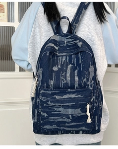 Detail of dark blue denim backpack with white jacquard patterns and cotton rope zipper