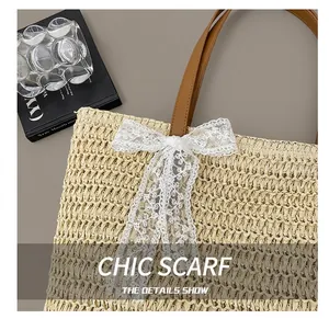 Close-up of beige straw tote bag featuring white lace bow detail and brown leather handle