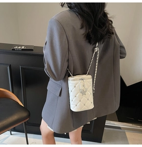 Détail du sac seau blanc matelassé avec breloque étoile et bandoulière en chaîne