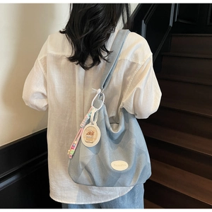 Détail d'un grand sac cabas bleu clair tissé avec pendentif capybara et écusson en cuir