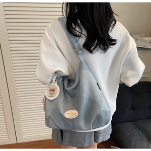 Détail du sac cabas en tricot bleu clair montrant le logo Banatu et la bandoulière réglable