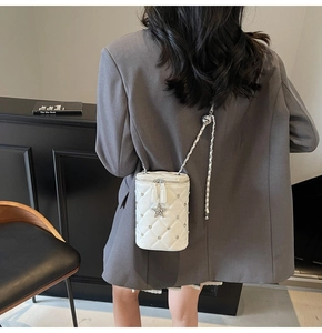 Détail du petit sac blanc matelassé avec pendentif étoile et bandoulière à la chaîne