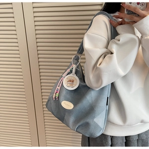 Détail du sac hobo bleu avec logo Banatu, breloque d'ours et pendentif en perles