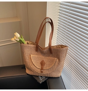 Detail of woven straw tote bag with brown PU leather straps and magnetic front pocket