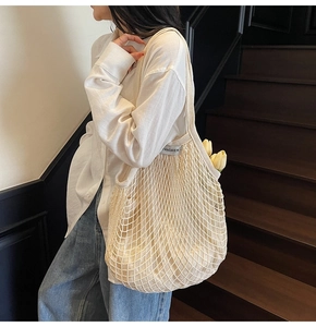 Detail van beige katoenen geweven tote bag met opengewerkt ontwerp en geweven merklabel