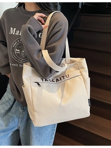 Minimalist large capacity canvas tote bag in off-white shown on model in outdoor setting