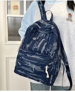 Detail of blue denim backpack showing white brushed texture and large zipper front pocket