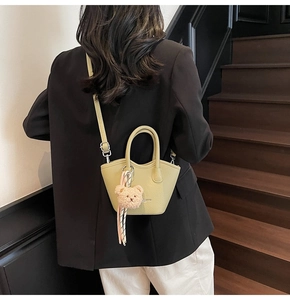 Sac seau chic vert olive avec breloque ours et foulard en soie porté par un mannequin