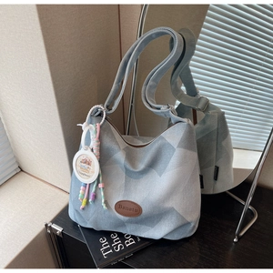 Détail du sac cabas en denim à carreaux bleu clair avec bandoulière et breloque perlée