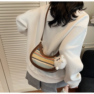 Detail of multi-color striped straw half-moon bag with leather strap and plush pompom charm