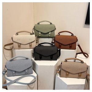 Multi-color leather crossbody bags displayed on minimalist geometric platforms