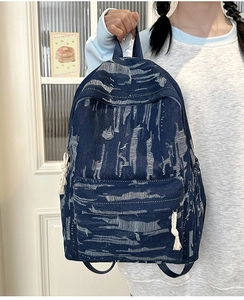 Detail of vintage denim backpack showing tiger-stripe washed texture and zip pocket