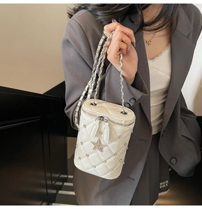 Détail du sac seau matelassé blanc avec breloque étoile et bandoulière chaîne sur modèle