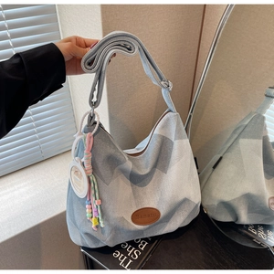 Détail du sac cabas en denim avec texture matelassée et accessoire de charme perlé bohème