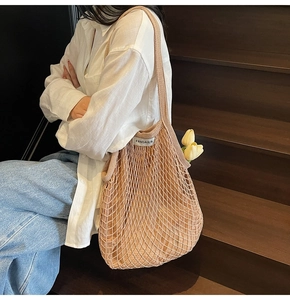 Detail van beige holle geweven mesh draagtas met stoffen voering op houten trappen