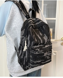 Detail of artistic brushstroke pattern backpack with stylish cotton tassel on zipper